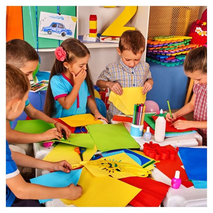 Group of children making colorful crafts at a table.