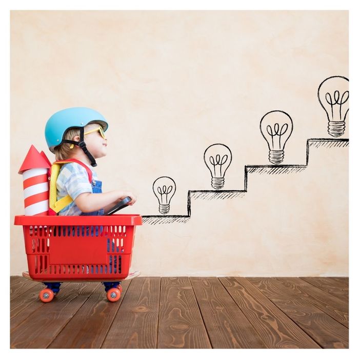 Child with helmet and rocket, climbing lightbulb steps.