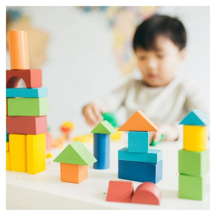 Child building colorful block towers on table.