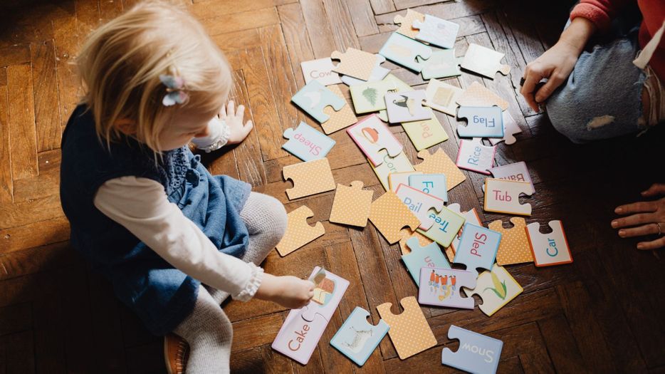 a child playing with puzzle-piece flashcards on the floor