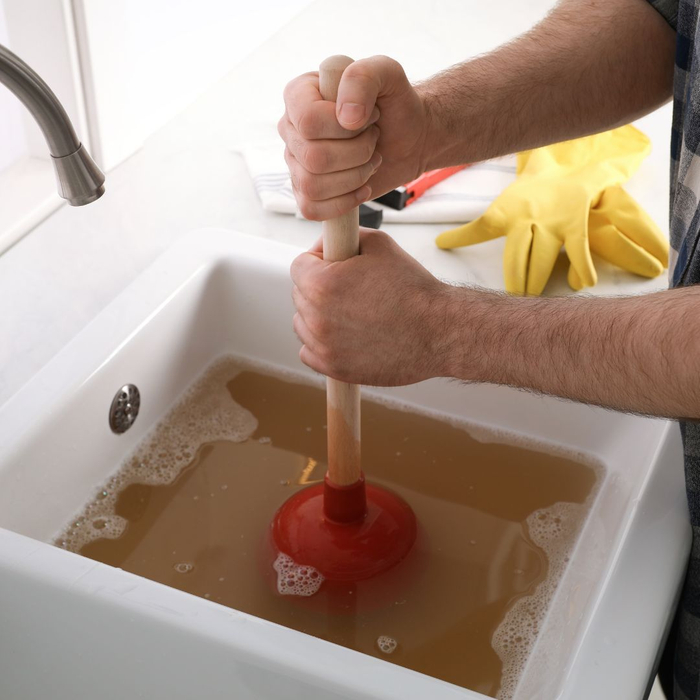 someone using a plunger on a clogged sink drain