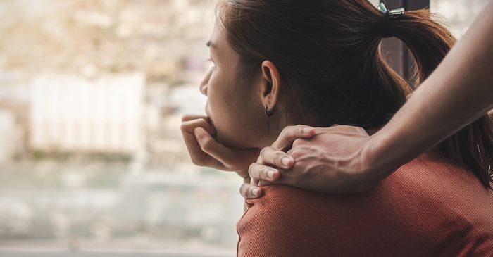 A woman looking out the window and being comforted