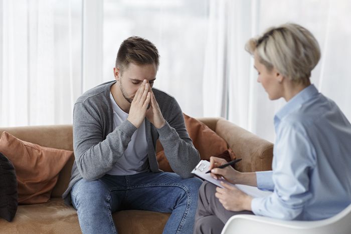 a young man holding his head in a therapy session