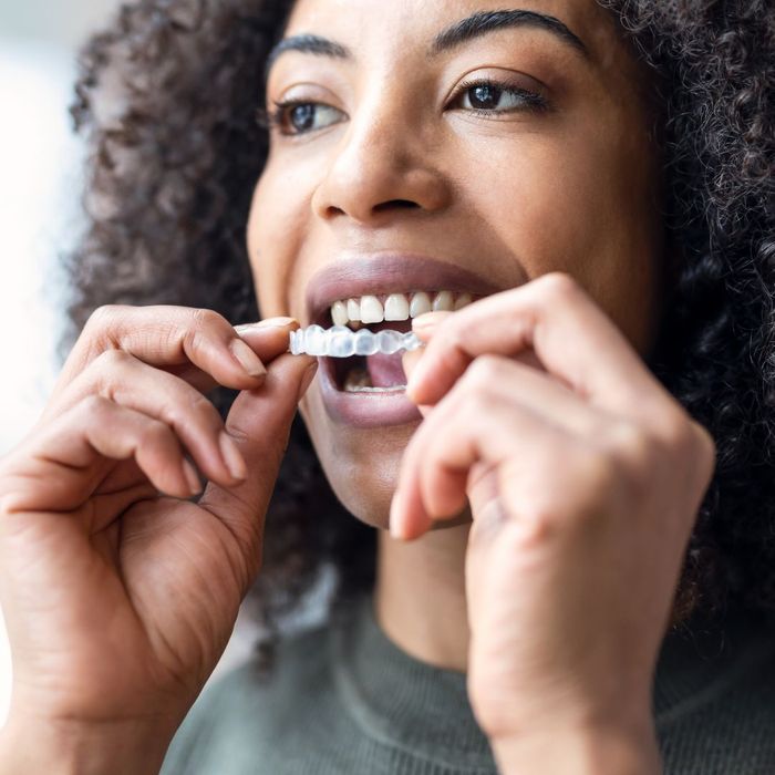 woman putting Invisalign into her mouth