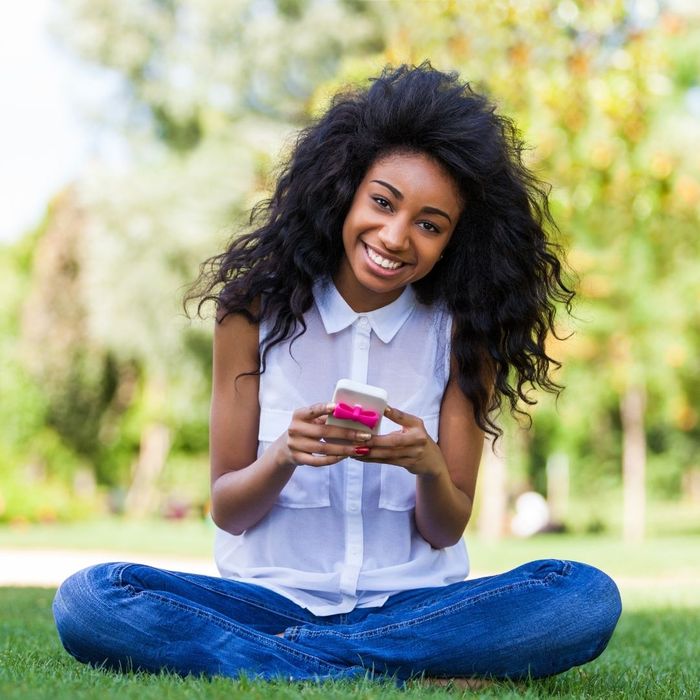 young woman with straight teeth smiling while using her phone young woman with straight teeth smiling while using her phone