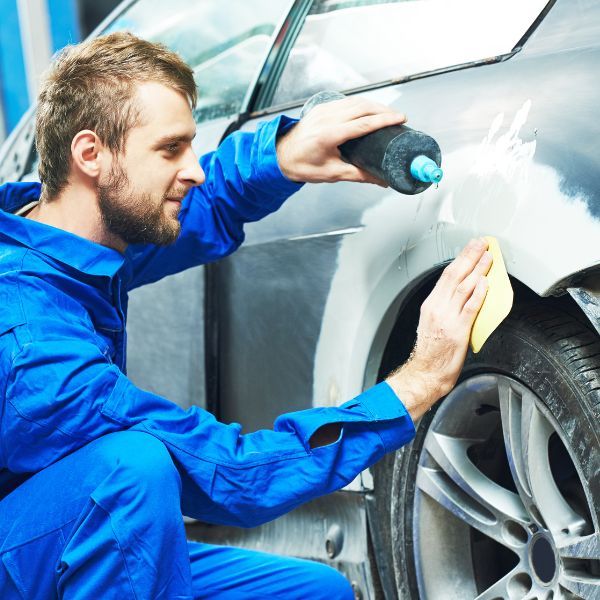 A mechanic reshaping a cars body