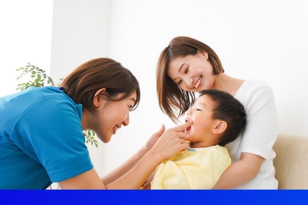 female nurse laughing with little boy and his mom