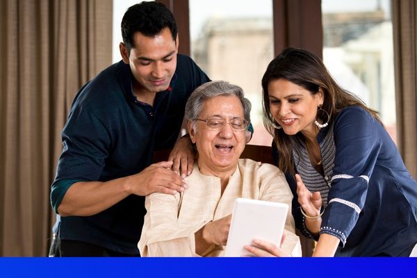 a man and a woman with an elderly man looking at an iPad