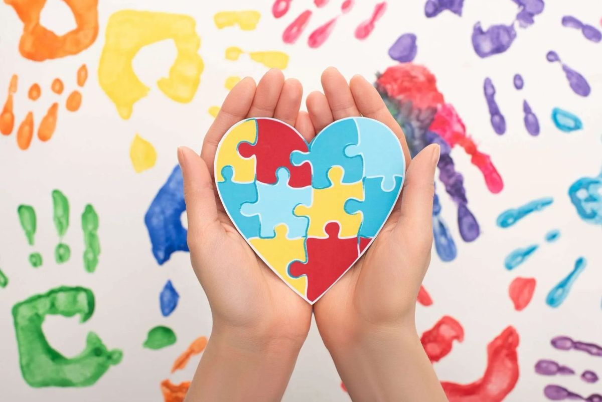 a womans hands holding a heart with puzzle pieces in it for Autism Awareness