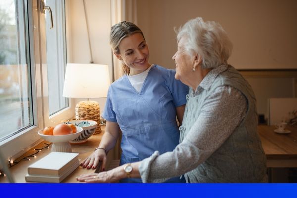 nurse talking to old woman by a window