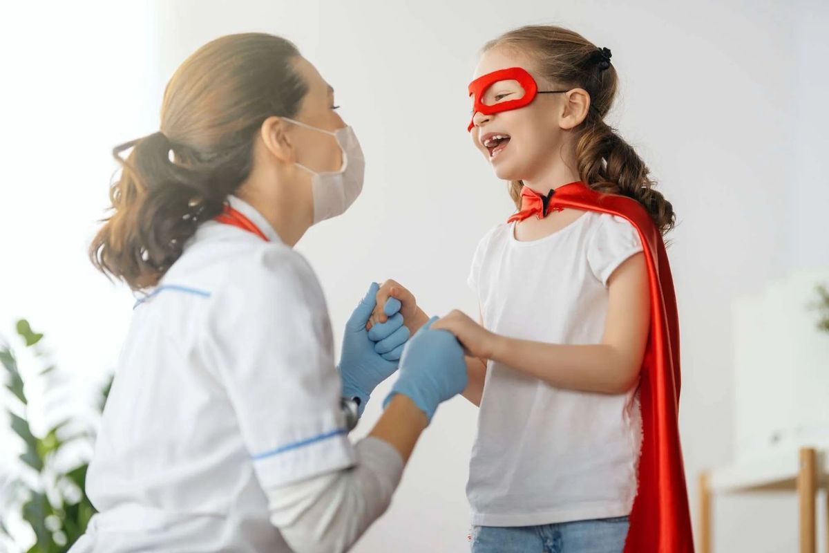 A doctor and a child dressed up as a superhero at a hospital
