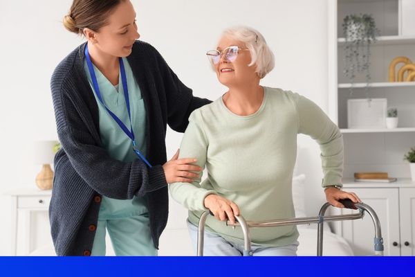 a female nurse helping an elderly woman with a walker get up from her seat