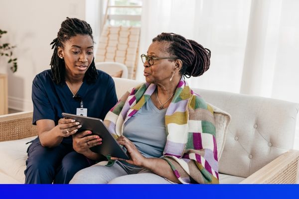 African American female nurse showing an elderly African American woman a tablet