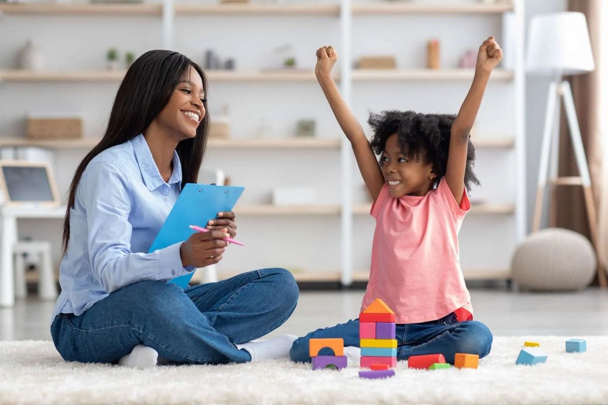 African American woman sitting on the floor with an African American child playing with blocks and smiling