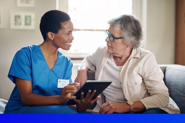 female nurse talking to elderly woman on the couch