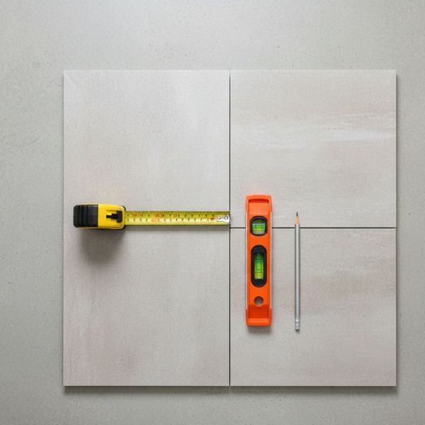 A top-down view of tile installation planning tools, including a tape measure and level.