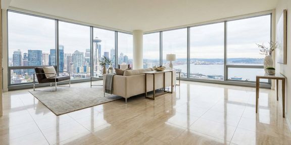 A luxurious modern living room with floor-to-ceiling windows overlooking a city skyline, featuring gleaming, highly polished beige stone tile flooring that reflects the light and furniture.