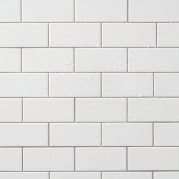 A close-up view of sparkling clean white subway tiles on a shower wall.