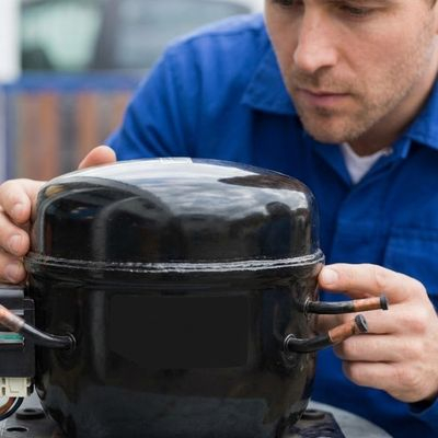 A technician inspects a failed commercial compressor.