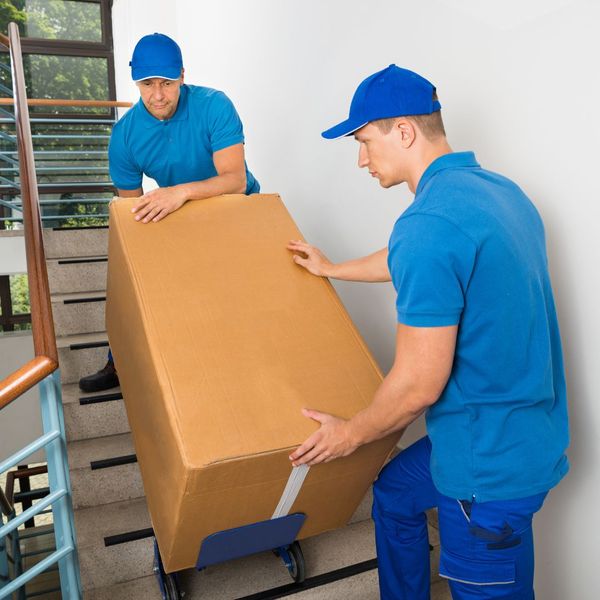 movers carrying large box down stairs