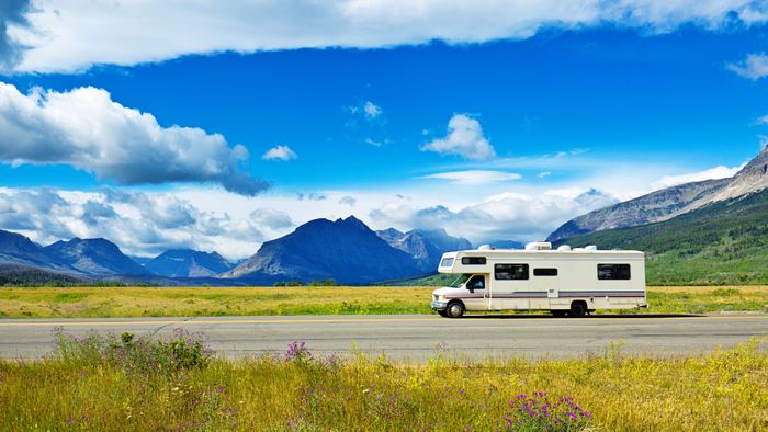 rv driving on open road with mountains in the background