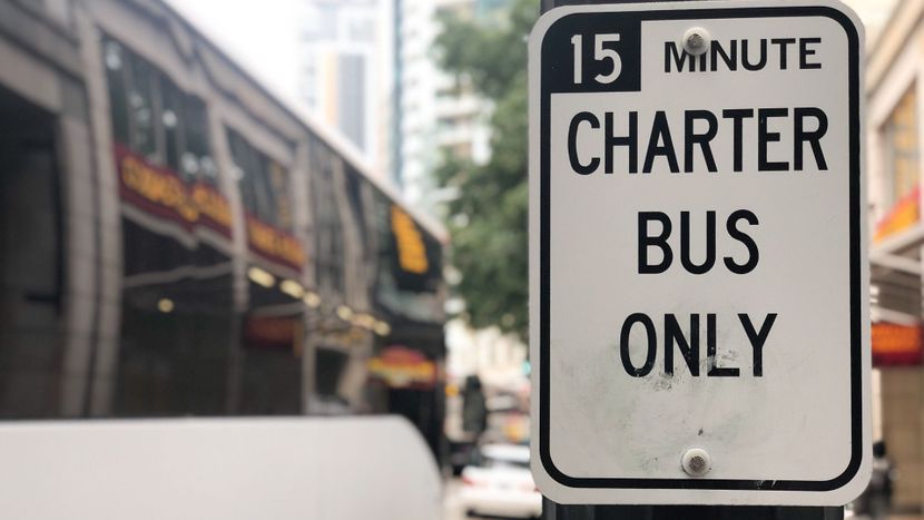 Charter bus parked in front of a sign that says  "15-minute charter bus only".