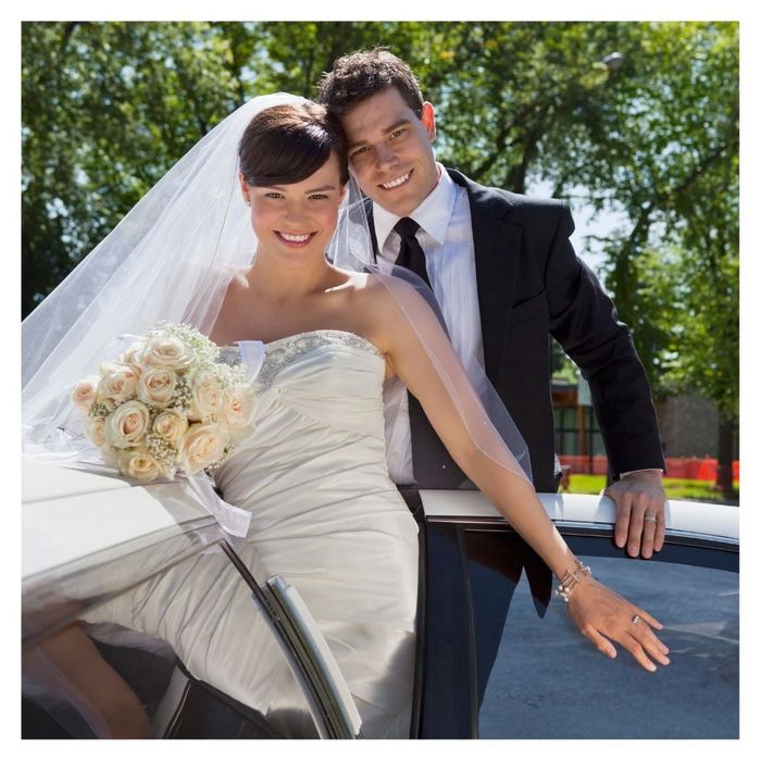 bride and groom posing with limo