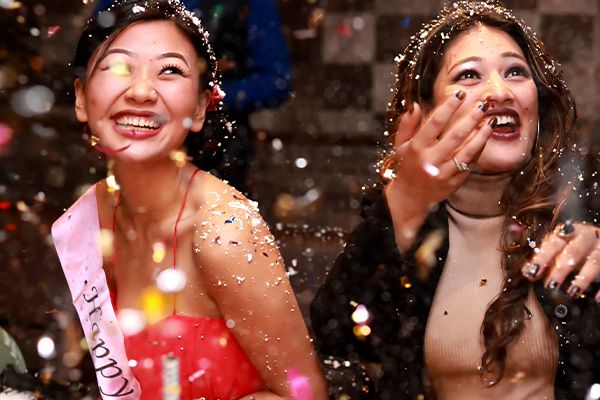 A birthday girl and her friend smiling as confetti falls