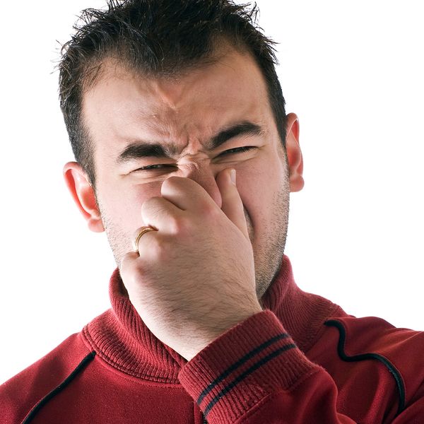 Image of a man holding his nose to avoid a bad smell