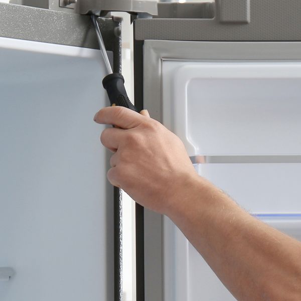 Image of a person doing maintenance on a commercial refrigerator.