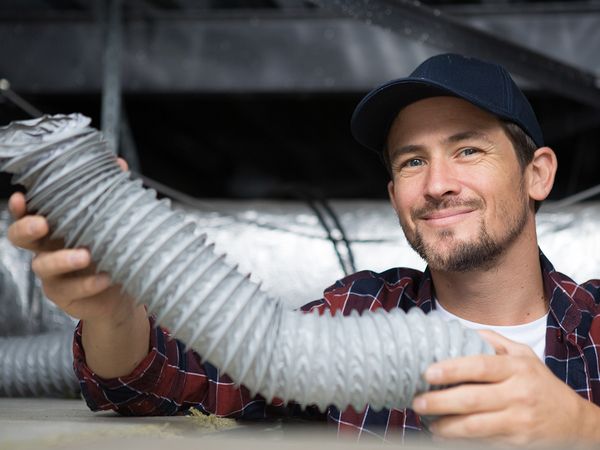 smiling HVAC tech working with ventilation