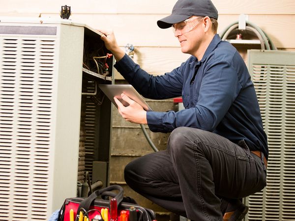 HVAC tech performing maintenance check on AC unit