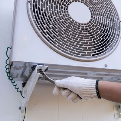 A technician repairing an outdoor air conditioning unit.