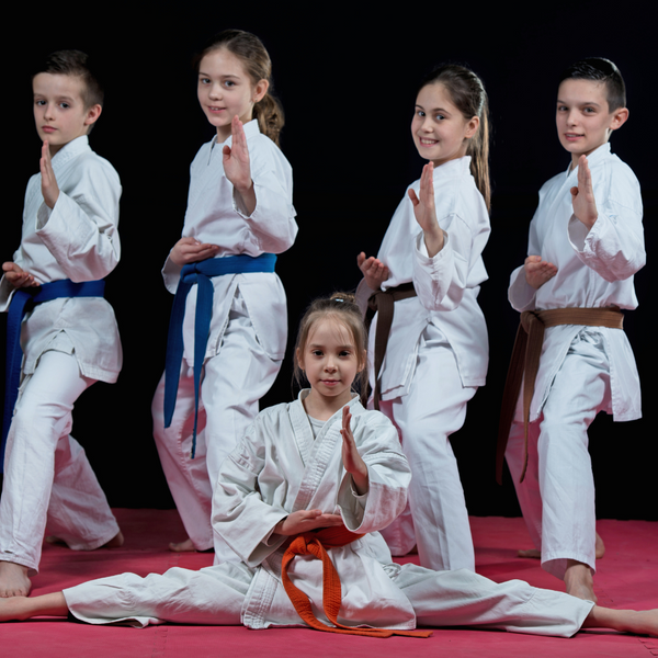 children looking happy in martial arts gear. 