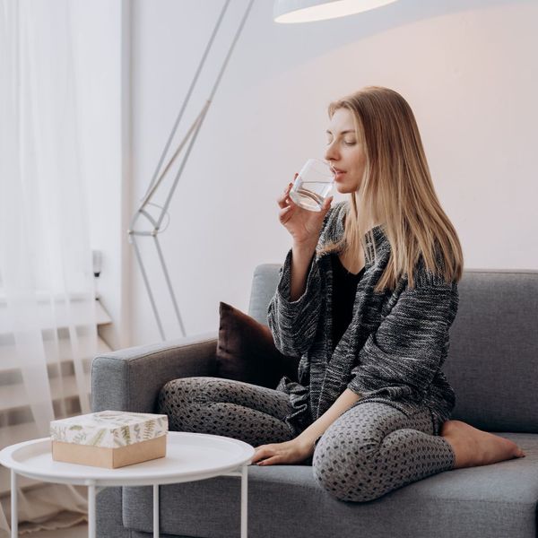 woman drinking water on couch