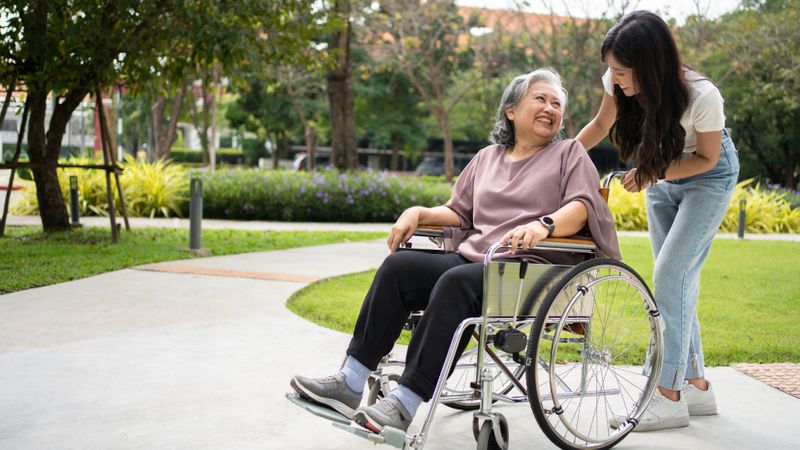 senior and caregiver smiling outside