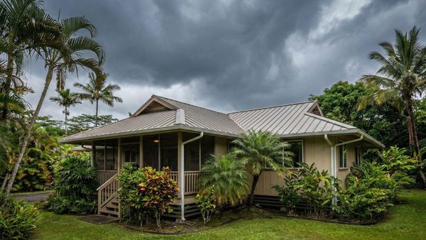 A house in a tropical location with rain gutters under a dark, cloudy sky.