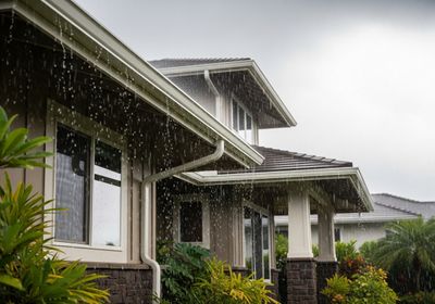 Rainwater cascading from house gutters during a downpour