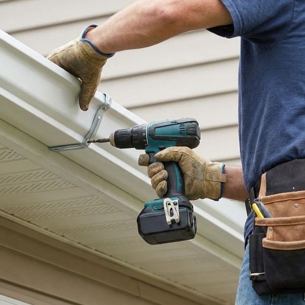 Professional contractor using a drill to install a gutter bracket.