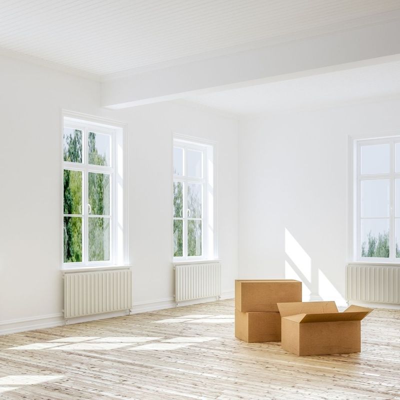 An empty, well lit living room with moving boxes in the middle