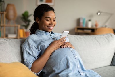 Relaxed expectant mother on clean couch after a Maid Affordable home cleaning in San Antonio, TX.