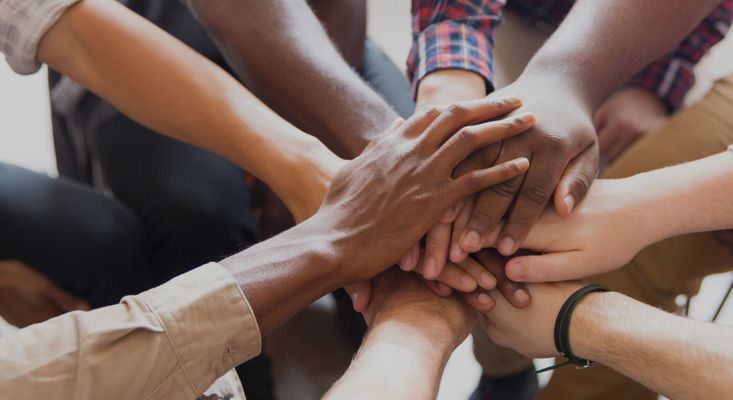 a group of people stacking their hands in group therapy Trust Riviera Living- Hero.jpg