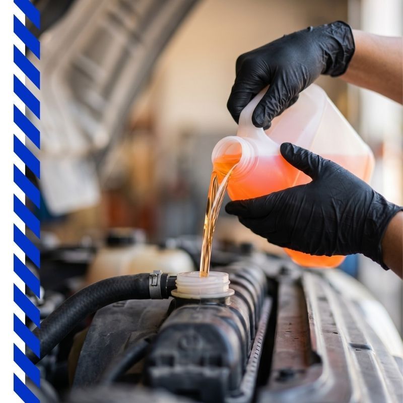 Mechanic wearing black gloves pouring fresh orange coolant into a vehicle radiator.