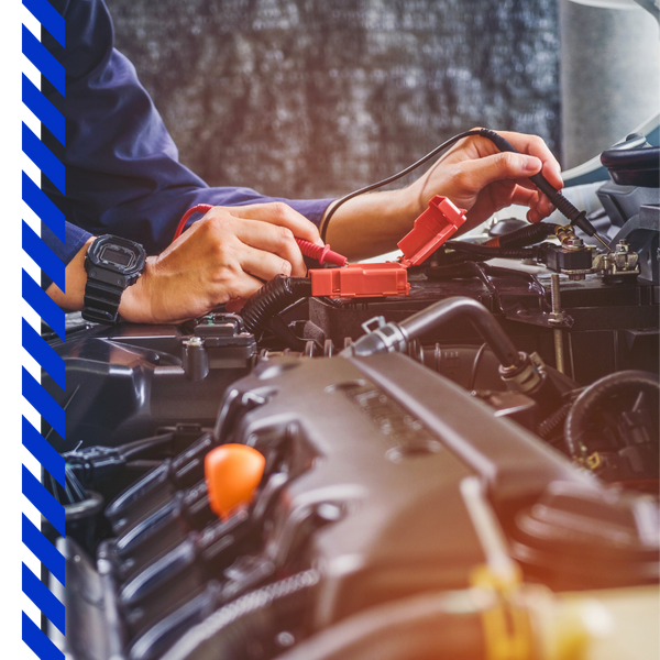 Close-up of a mechanic's hands using a digital multimeter to test a vehicle's battery and electrical system.