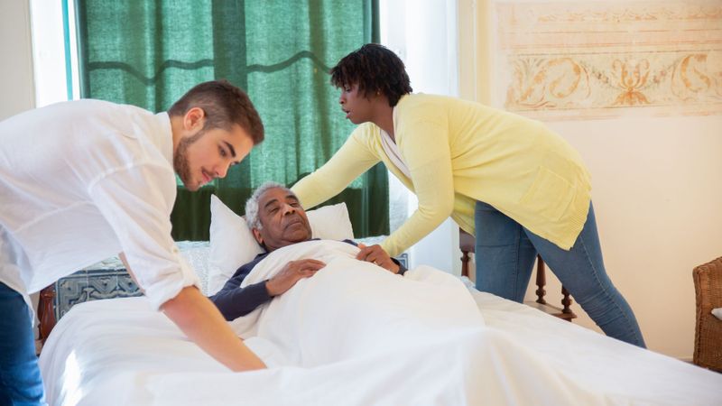 caregivers with man in bed