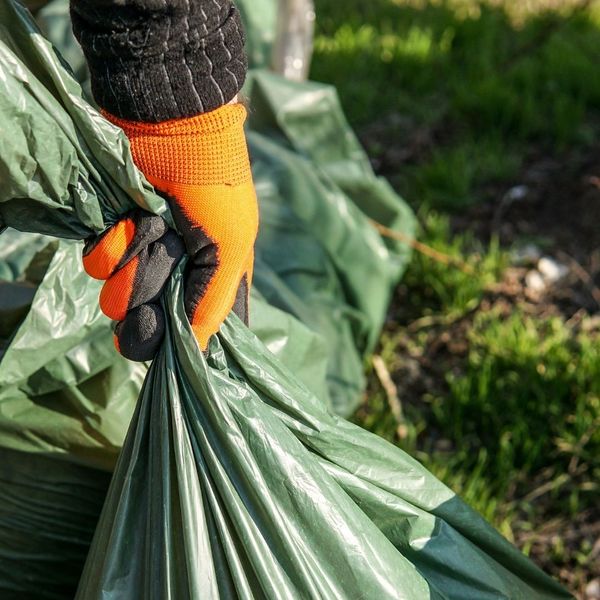 person picking up a trash bag with gloves on