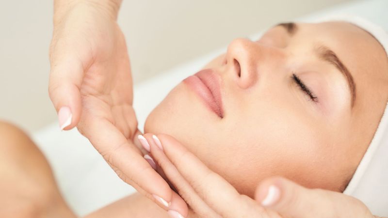 woman at spa for facial, clinician's hands on patient's chin
