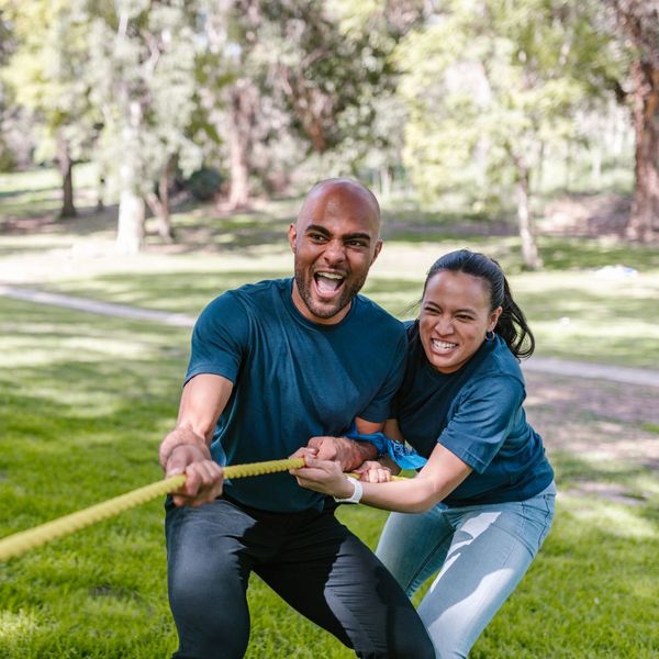 Man and a woman pulling on a rope, playing tug-of-war.