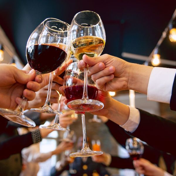 People raising their wine glasses to cheers. 