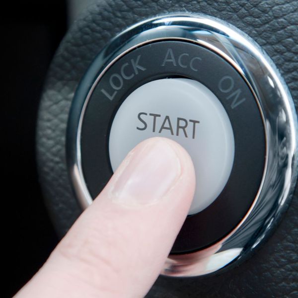 finger pushing the Push-to-Start ignition in the car